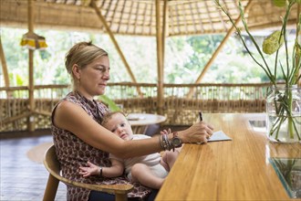 Caucasian woman with baby writing at table