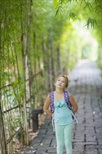 Caucasian girl walking on stone path under bamboo trees
