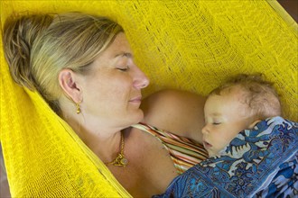 Caucasian mother and baby sleeping in hammock