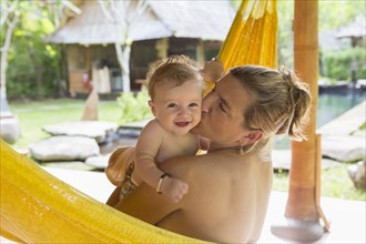 Caucasian mother kissing baby in hammock