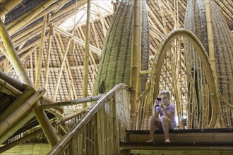Caucasian girl using cell phone in bamboo hotel