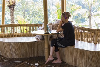 Caucasian woman using laptop on bamboo patio