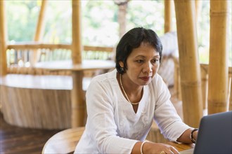 Balinese woman using laptop at table
