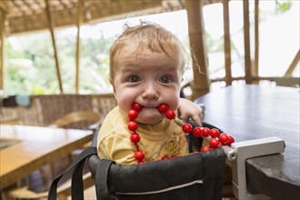 Caucasian baby playing with beads in high chair