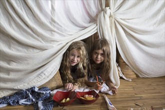 Caucasian girls playing in blanket fort