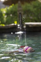 Caucasian girl spraying water in swimming pool