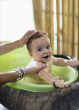 Caucasian mother bathing baby in plastic tub