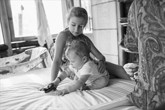 Caucasian girl and baby boy playing on bed
