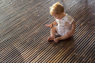 Caucasian baby playing on bamboo floor