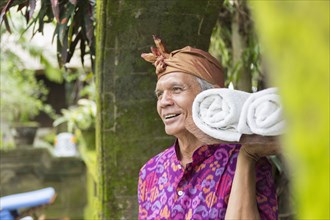 Balinese worker carrying rolled towels