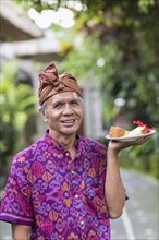 Balinese server carrying plate of food