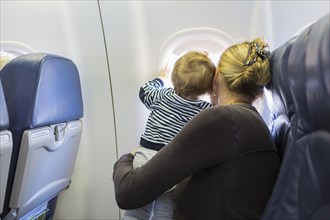 Caucasian mother and baby looking out airplane window