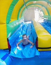 Caucasian girl laughing on water slide