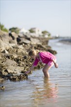Caucasian girl exploring on rocky beach