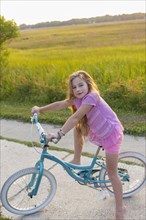 Caucasian girl riding bicycle on rural street