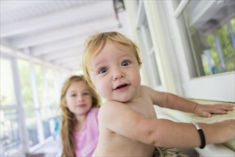 Caucasian baby and sister sitting on porch