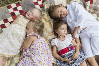 Caucasian children laying on blanket outdoors