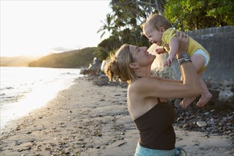Caucasian mother holding baby on beach