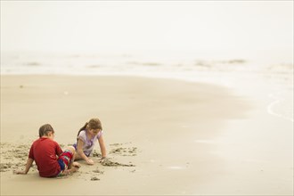 Caucasian children playing in sand on beach