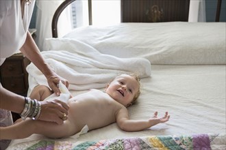Caucasian woman changing toddler's diaper