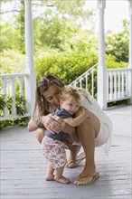 Caucasian mother hugging toddler on porch