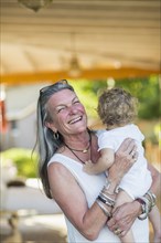 Caucasian older woman holding grandson on porch