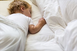 Caucasian toddler asleep in bed