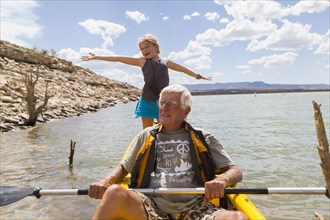 Older Caucasian man rowing kayak with granddaughter
