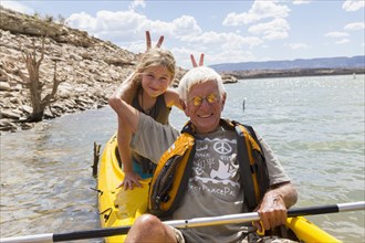 Older Caucasian man posing in kayak with granddaughter