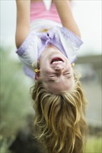 Caucasian girl hanging upside down outdoors