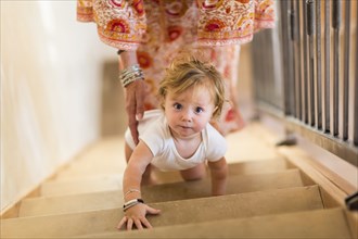 Caucasian mother helping baby son climb stairs
