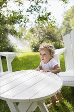 Caucasian baby boy sitting at table in backyard