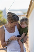 Caucasian mother and baby son using cell phone