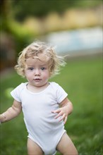 Caucasian baby boy walking in grass