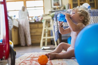 Caucasian baby boy drinking water in kitchen