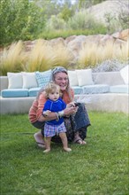 Caucasian grandmother hugging baby grandson in backyard