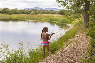 Caucasian girl fishing in rural lake