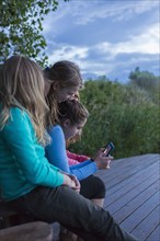Children using cell phone together outdoors