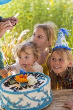 Family celebrating birthday together outdoors
