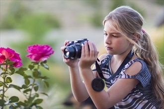 Caucasian girl photographing flowers outdoors