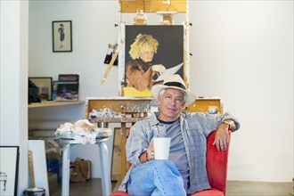 Older Hispanic artist relaxing in studio