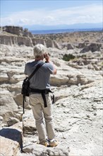 Older Caucasian man photographing rock formations