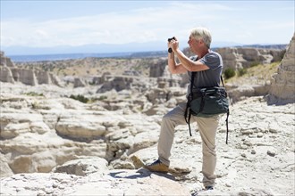 Older Caucasian man photographing rock formations