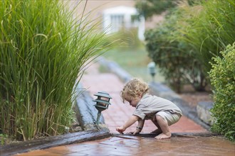 Caucasian baby boy playing on brick walkway