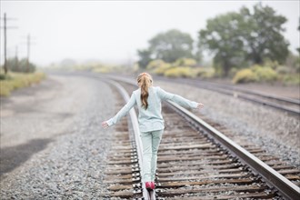 Caucasian girl balancing on train tracks