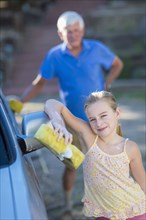 Caucasian grandfather and granddaughter washing car outdoors