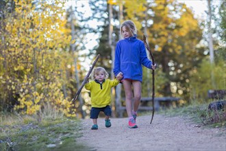 Caucasian children hiking on dirt path in forest