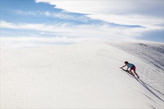 Caucasian girl climbing sand dune