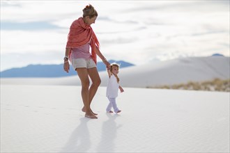 Caucasian mother and son walking on sand dune