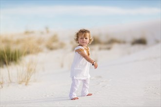 Caucasian boy walking on sand dune
